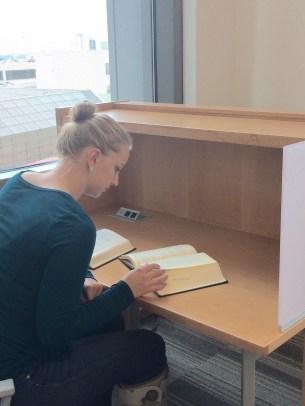student reading a book in a study carrel in the law library.